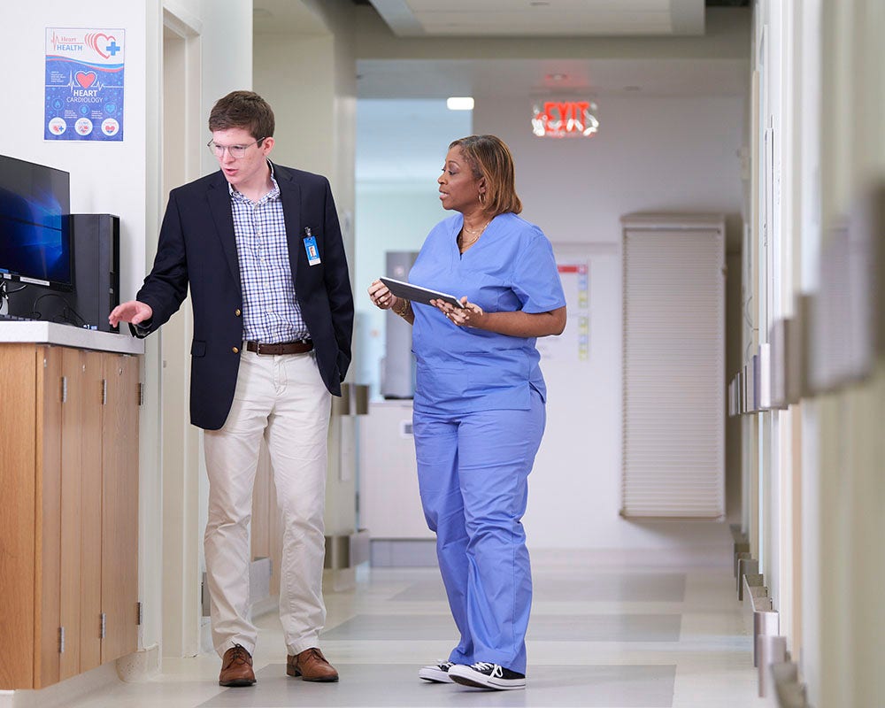 A person in scrubs is talking to a person in business attire.